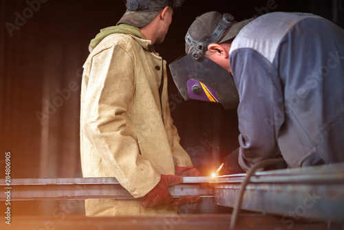 Two welders straighten metal profile