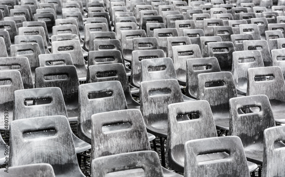 Fototapeta premium Rows of empty gray chairs in the rain