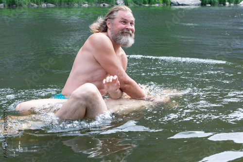 Fotografie, Obraz a bearded man with a kind face dips a man in the water