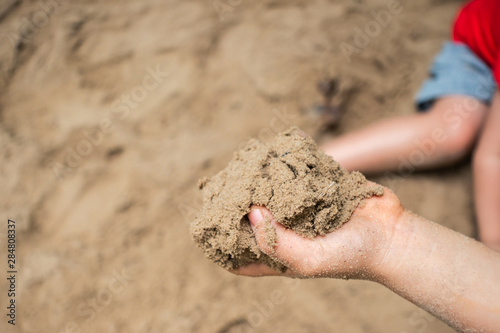 Hands of child playing with sand outdoor