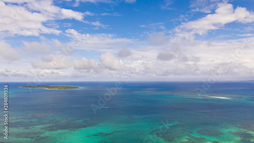 Seascape with coral reefs and islands. Tropical climate and nature of the Philippines. A small island on the atoll.