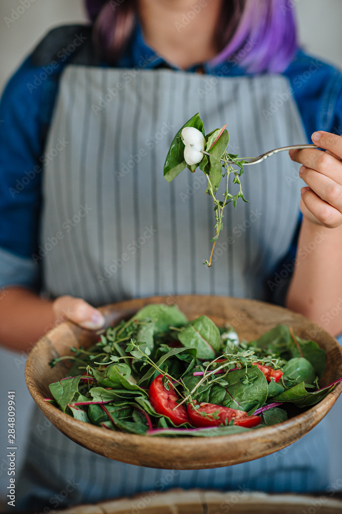 hands of the girl cut lettuce on a wooden table, a woman prepares a veggie salad, healthy food, a knife chops greens