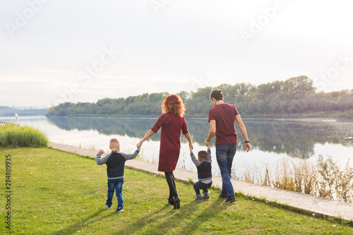 Parent  childhood and nature concept - Family playing with two sons by the water