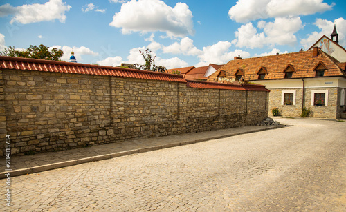 Ukrainian old city back street alley way with stone wall paves road and monastery small building in colorful day time and clear weather 