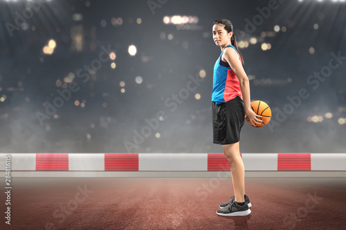 Asian woman basketball player holding the ball on her back