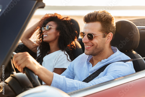 Photography Beautiful young multiethnic couple riding in a convertible