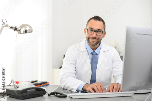 Εκτύπωση καμβά portrait of a handsome man male doctor in medical practice office working on com