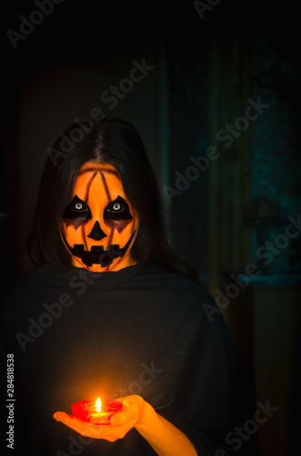 Frightening pumpkin face character hold a candle. A portrait of a halloween creature