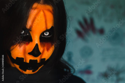 Spooky pumpkin face of a halloween creature on dark background with ritual symbols