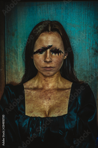 Creepy portrait of young woman without eyes on rough azure background