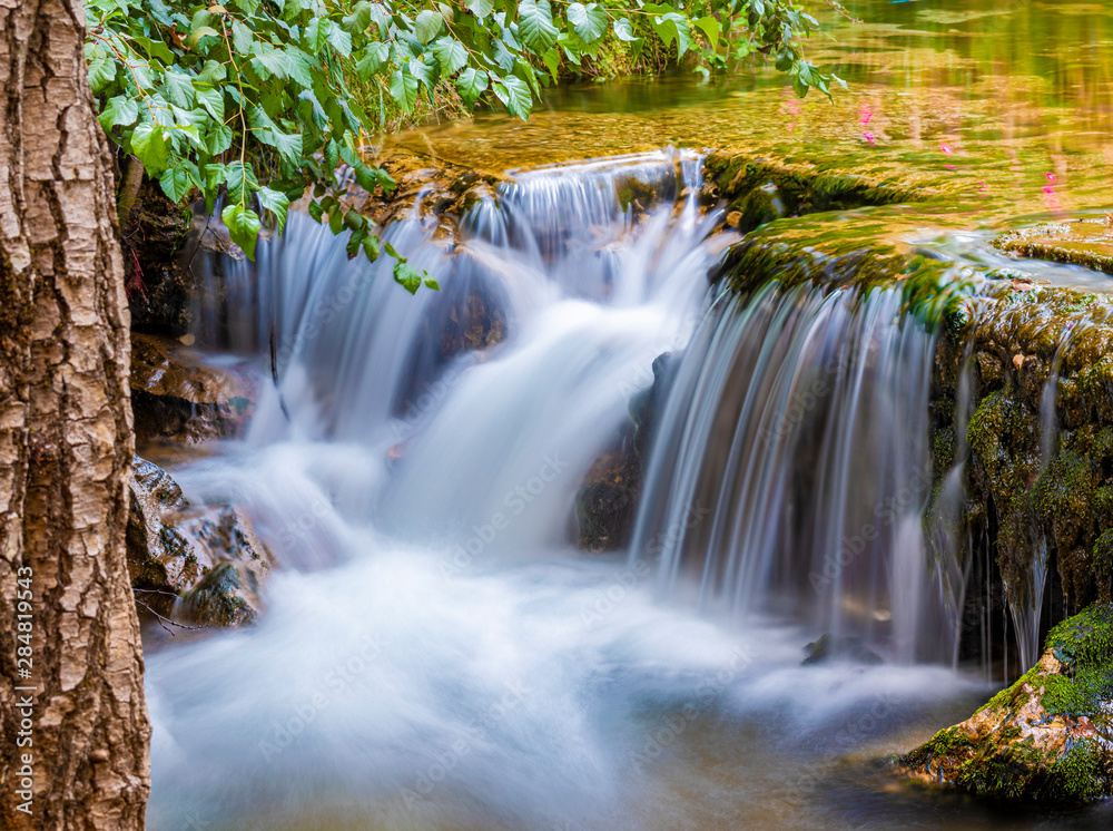 Small mountain waterfall on the rocks covered with moss in the forest Small mountain waterfall on the rocks covered with moss in the forest