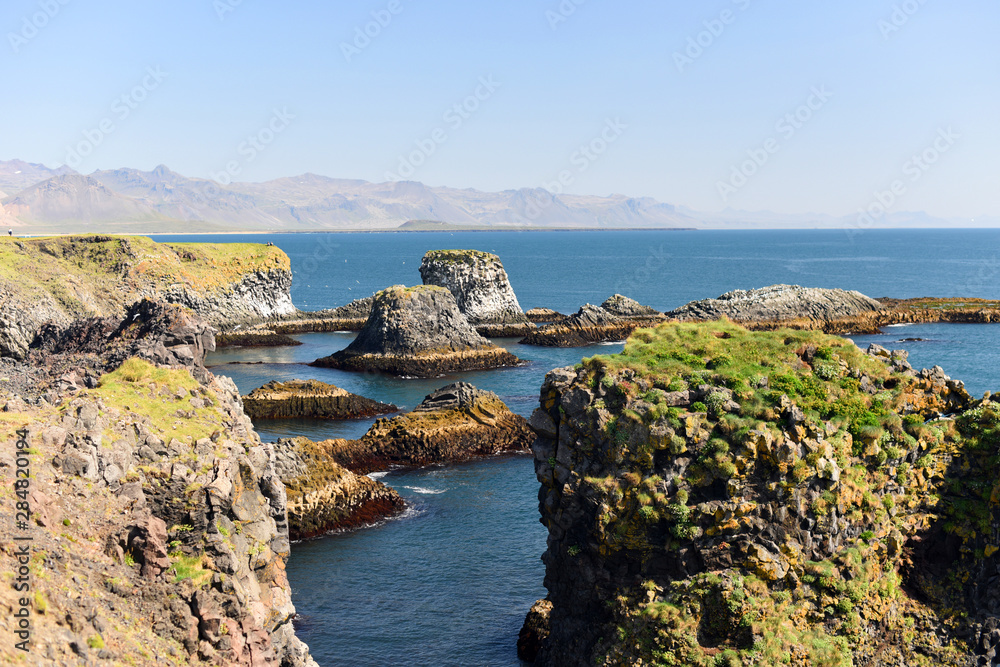 West coast sea cliffs of Snaefellsnes Peninsula on Iceland.Pure blue water with high cliffs above sea. Beautiful colourful scenic view of basalt rock reef.