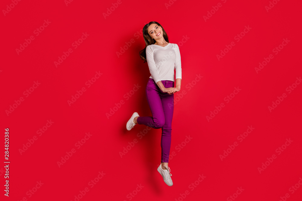 Full length body size photo of jumping shy cute fascinating woman admiring something while isolated with red background