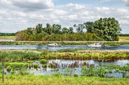 Two small yachts passing a group of trees at the new Reevediep channel near Kampen, The Netherlands, created to prevent flooding of the river IJssel photo