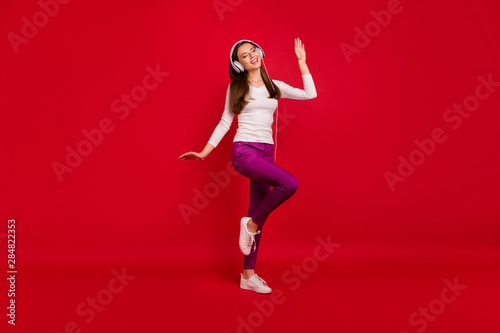 Full length body size photo of rejoicing gorgeous girl appreciating music dancing alone in front of red background she is isolated with