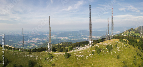 Drone aerial view of a group of towers for telecommunications, television broadcast, cellphone, radio and satellite on Linzone mountain peak. Electromagnetic and environmental pollution. Italian Alps