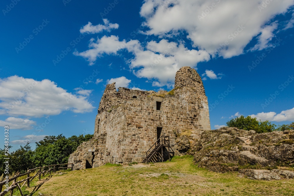 Primda, Czech Republic - August 11 2019: Old ruin of oldest stone castle in the Czech Republic, from 12th century, standing on a high hill on a rock. Sunny summer day with blue sky and white clouds.