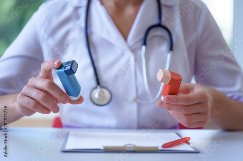 Asthma inhalers in doctor hands for asthmatic patient during medical consultation and examination. Healthcare and asthma treatment