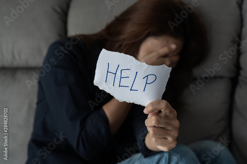 Bild auf Leinwand Lonely women sitting alone with depressed expression and showing a paper with a help text