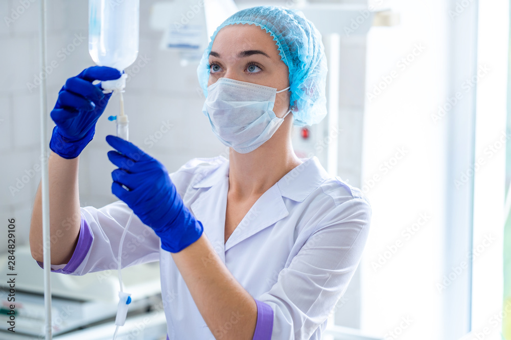 Nurse in medical uniform preparing drop counter to a patient for procedure in hospital Nurse in medical uniform preparing drop counter to a patient for procedure in hospital