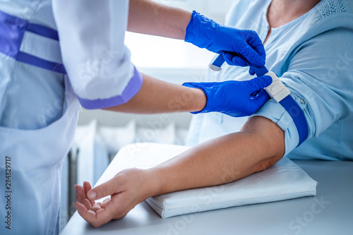 Nurse in rubber blue medical gloves takes blood from a vein for laboratory test. Medical tests
