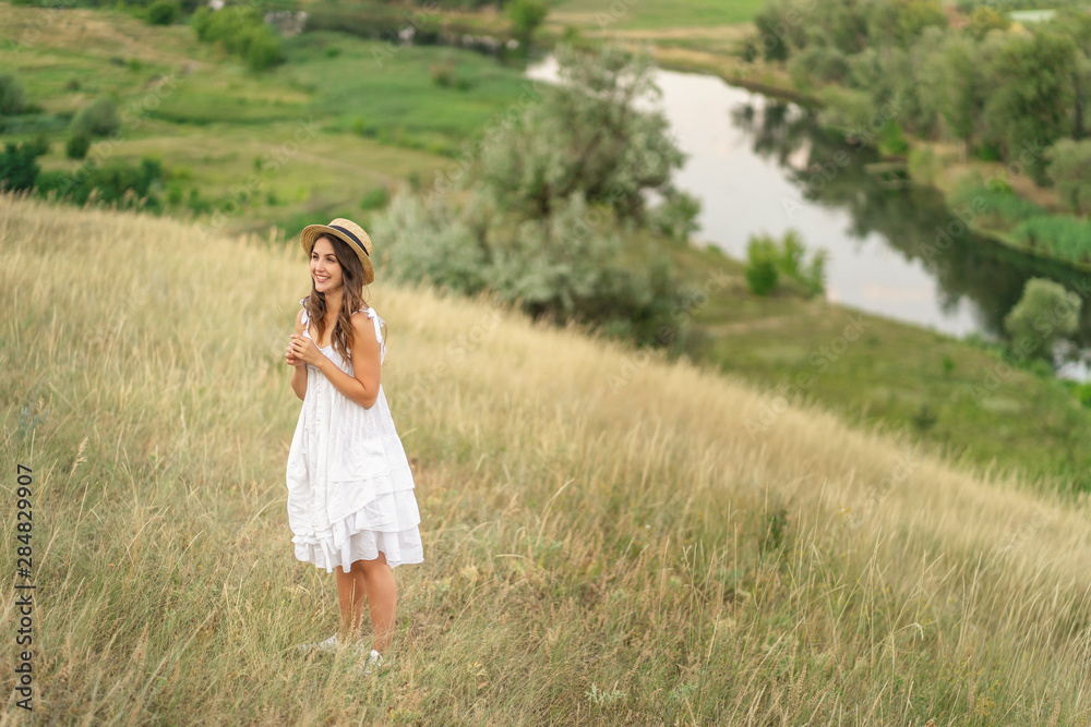 Smiling woman in white dress is walking near the river. Summer nature. outdoor Smiling woman in white dress is walking near the river. Summer nature. outdoor