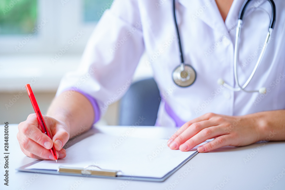 A doctor with a stethoscope writing the diagnosis and treatment of the disease in a clipboard during a medical consultation. Healthcare A doctor with a stethoscope writing the diagnosis and treatment of the disease in a clipboard during a medical consultation. Healthcare
