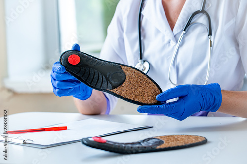 Nurse holds orthopedic insoles for the treatment and prevention of flat feet. Foot care and wearing comfortable shoes photo