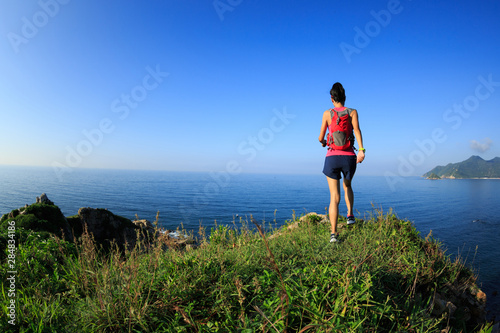 Young fitness woman running on seaside mountain trail © lzf