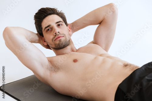 Young sports man make abs exercise isolated over white background.