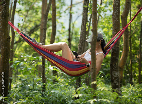 Relaxing in hammock,using smartphone in tropical rainforest