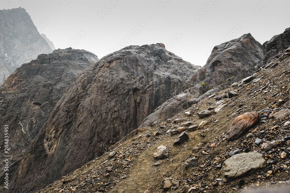 A sloping slope covered with loose stones. Difficult climb to Aktru. Beautiful views of the rounded mountains on a tour of the nature of Altai land. High  pyramidal mountain. Siberia. Russia.