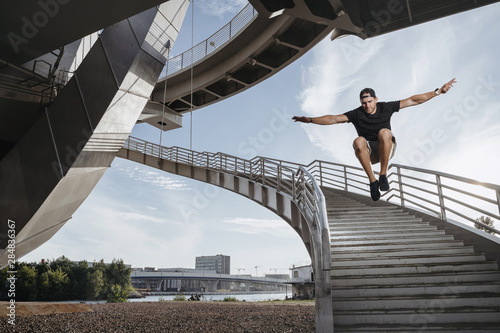 Parkour athlete doing a beautiful high jump from the stairs photo