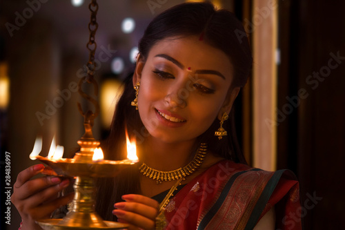 young woman lighting a lamp	 photo