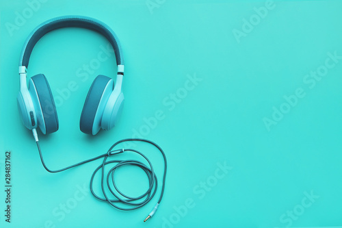 Turquoise headphones on a colored background. Music concept with copyspace. Colored headphones isolated