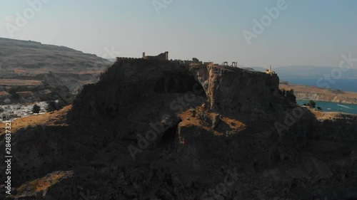 fortress silhouette on brown rocky cliff top lit by sunlight photo