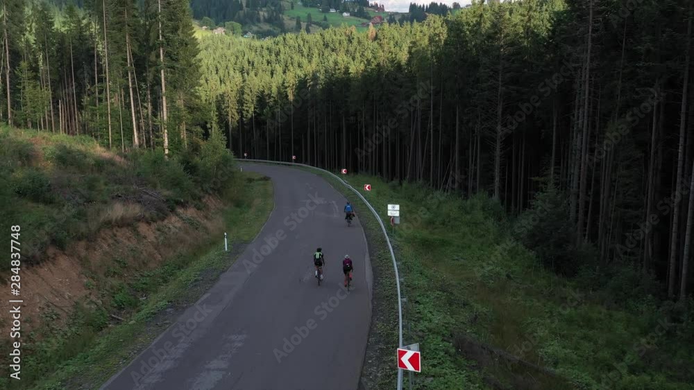 Aerial shot of man and woman cycling on the asphalt road in mountains. Travel by bicycle. Outdoor activities concept