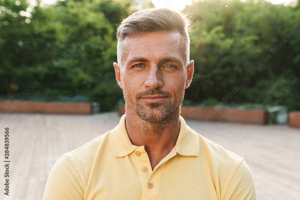 Image closeup of confident middle-aged man looking at camera while walking in summer park Image closeup of confident middle-aged man looking at camera while walking in summer park