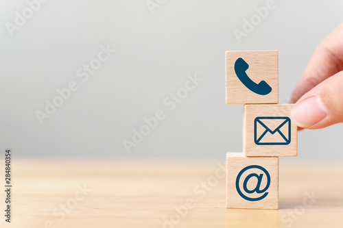 Hand putting wooden block cube symbol telephone, email, address. Website page contact us or e-mail marketing concept