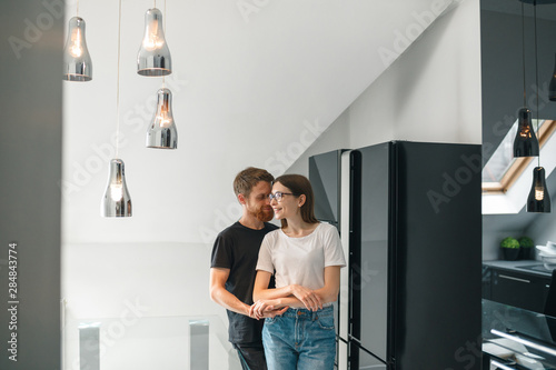 Fun while cooking. Beautiful pair is standing on the kitchen and hugging. Loving pair is ready to cook a delicious dinner