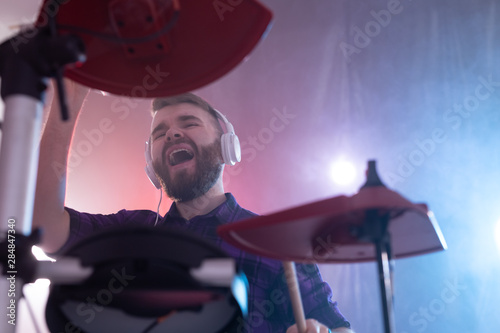 Drums, music and people concept - emotional man playing on elecronic drums, it's his hobby photo