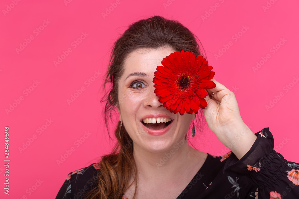 Flowers, emotions and people concept - woman closed her eye with gerbera on pink background Flowers, emotions and people concept - woman closed her eye with gerbera on pink background