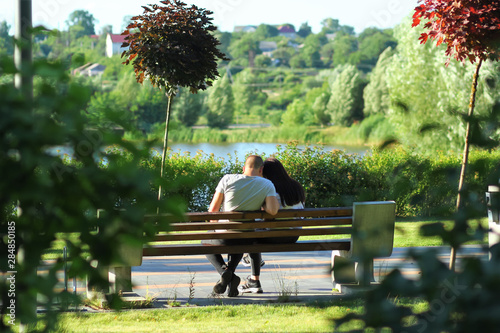 Cuddling couple on the bench in the summer park