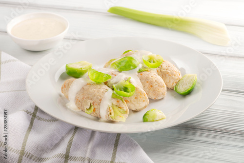 Tasty chicken cutlets with cabbage and carrots with sour cream sauce on a white plate