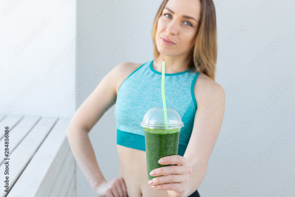 Healthy, sport, diet and people concept - Successful fitness urban woman recommending detox smoothie Healthy, sport, diet and people concept - Successful fitness urban woman recommending detox smoothie
