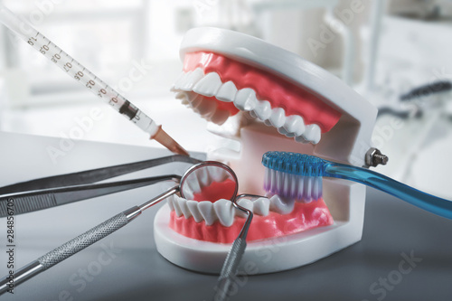 dental health and treatment - dentist tools with teeth model in clinics office