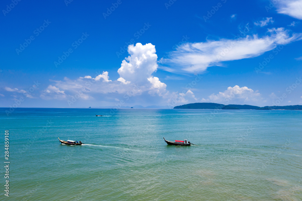 Aerial view of traditional longtail boats floating on a turquoise and clear ocean in Thailand.