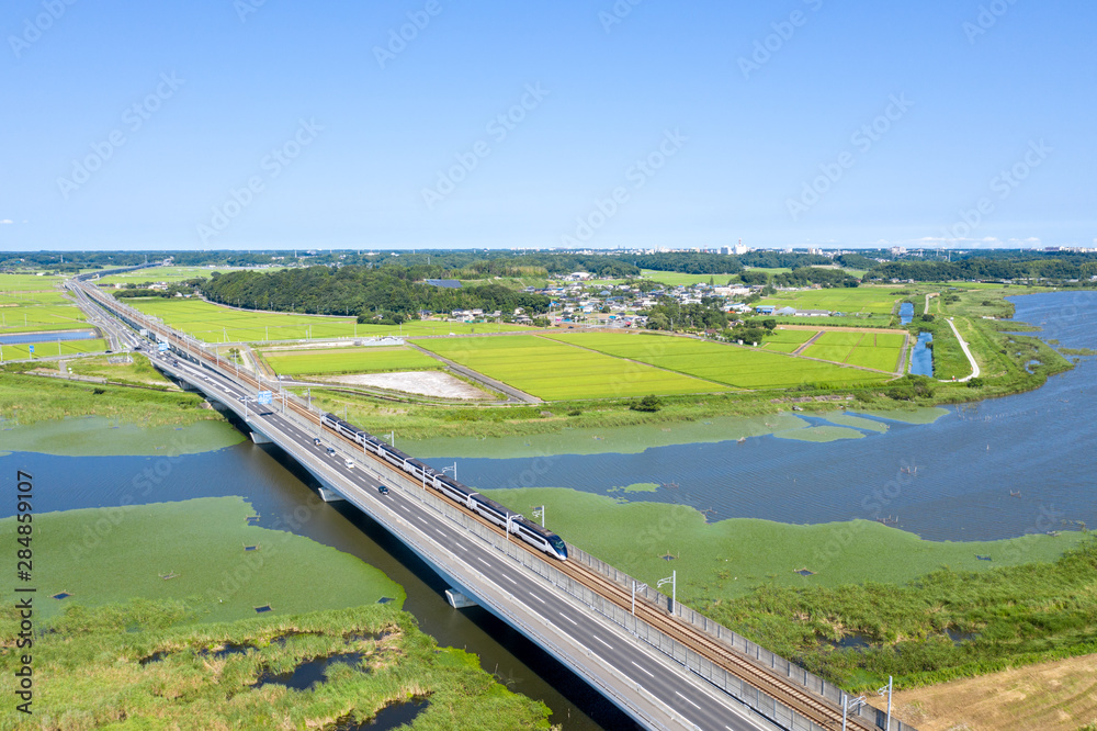 Obraz premium 千葉県の印旛沼を渡る京成スカイライナーと国道464号線を俯瞰撮影