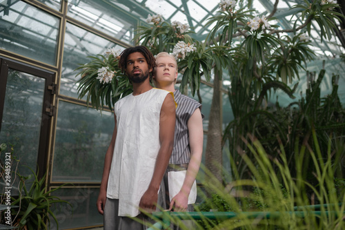 Blonde man standing behind dark-skinned bearded man