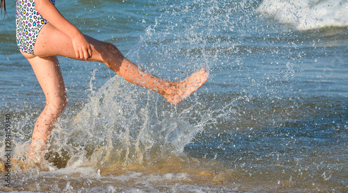 Running young girl legs on the beach and copy space